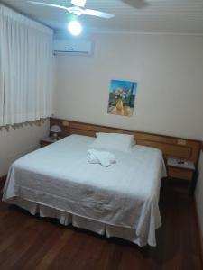 a bedroom with a white bed with two towels on it at Hotel Primavera in Bento Gonçalves