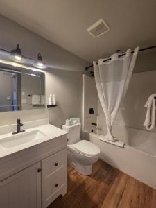 a bathroom with a toilet and a sink and a tub at The Baker Hotel in Cranbrook +66 photos