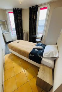 a bedroom with a large bed and two windows at Le Grand Café in Châtillon