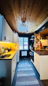 a kitchen with white cabinets and a wooden ceiling at Savupirtti 1819 in Pudasjärvi