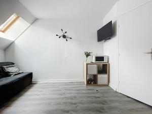 a living room with a couch and a tv on a wall at Le Petit Jules in Dijon