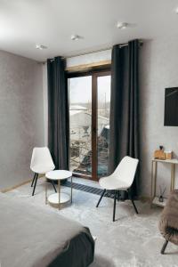 ein Schlafzimmer mit zwei Stühlen, einem Bett und einem Fenster in der Unterkunft Sofa Boutique Hotel & SPA in Sumy