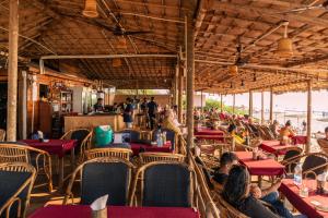 a group of people sitting at tables in a restaurant at Blue Corner Beach Huts & Restaurant in Benaulim