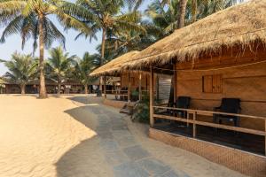 a building with a straw roof on the beach at Blue Corner Beach Huts & Restaurant in Benaulim