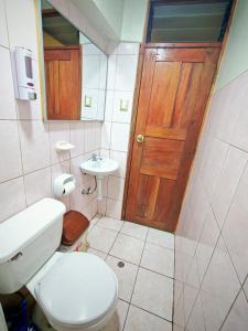 a bathroom with a toilet and a sink and a door at Cusco Hawka Pacha hostal in Cusco