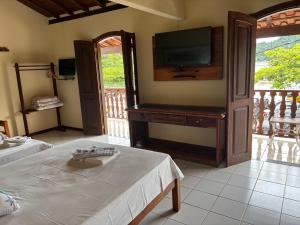 a living room with a tv and a bed at FLATS e SUÍTES NATIVA in Paraty