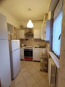 a kitchen with white cabinets and a white refrigerator at La casetta di Nonno Carlo a due passi dall'ospedale in Torrette +15 photos