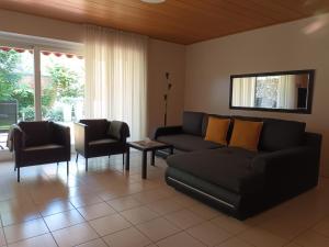 a living room with a black couch and two chairs at Apartment am Vechtesee in Schüttorf