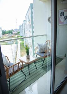 a balcony with two chairs and a table at Serenity Haven Luxe 2BR, Pool, Wi-Fi, AC, Netflix , DSTV, Gated, Sakumono in Agblesia