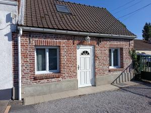 a red brick house with a white door at maison Le Wetz in Sainte-Marie-Kerque