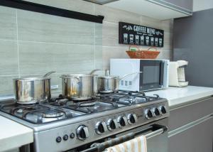 a stove with four pots on it in a kitchen at Serenity Haven Luxe 2BR, Pool, Wi-Fi, AC, Netflix , DSTV, Gated, Sakumono in Agblesia +41 photos