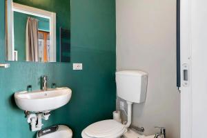 a green bathroom with a toilet and a sink at Mistral Holidays - Minisuite Marina in Marina di Carrara