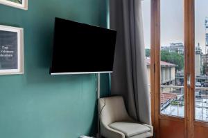 a tv on a wall next to a chair and a window at Mistral Holidays - Minisuite Marina in Marina di Carrara