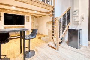 a living room with a table and a tv and stairs at La bulle étoilée in Périgueux