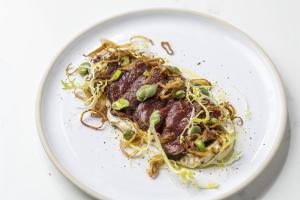 a plate of food with noodles and green onions at Holmes Hotel London in London