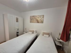 two beds in a room with white walls at Logis Hotel- Restaurant La Haie Des Vignes Séminaires et Evènementiel in Allain +60 photos