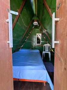 a bed in a green room with a chair at Camping Gnomo Místico in Olivença