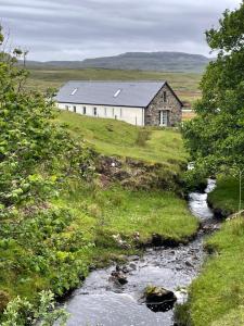 an old building on a hill next to a river at Dunvegan Steading Bed and Breakfast in Dunvegan