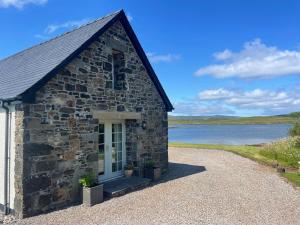 a small stone building with a lake in the background at Dunvegan Steading Bed and Breakfast in Dunvegan