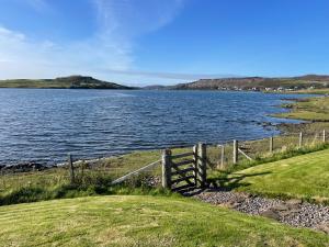 a fence next to a large body of water at Dunvegan Steading Bed and Breakfast in Dunvegan +13 photos