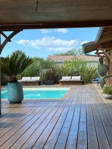 a patio with a pool and a wooden deck at La cabane 62 in La Teste-de-Buch