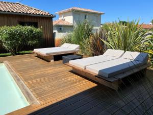 a wooden deck with two benches and a swimming pool at La cabane 62 in La Teste-de-Buch