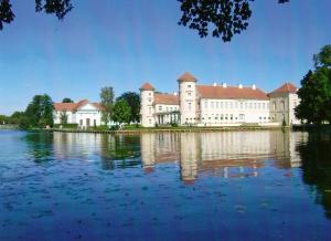 a large building with a lake in front of it at Kleine Ferienwohnung in der Natur in Rheinsberg