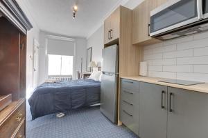 a kitchen with a refrigerator and a bed in a room at Le Cavalier du Moulin - M11 in Quebec City +122 photos