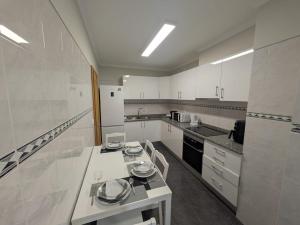 a large white kitchen with white cabinets and appliances at Pátio do Garajau Apartamento T2 com estacionamento e varanda perto do Cristo Rei in Caniço +5 photos