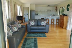 Una sala de estar con un sofá y una cocina. en Kohinui Glade Holiday Cottage, en Parua Bay