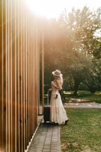 a woman in a white dress and hat with a suitcase at Przystanek Roztocze- leśne SPA, Jacuzzi & sauna in Susiec