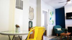 a dining room with a glass table and yellow chairs at Seaside Flamingo Retreat in Oceano