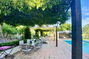a patio with a table and chairs next to a pool at Finca La Alcolehuela in Santa Elena