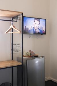 a flat screen tv hanging on a wall next to a refrigerator at Foools Inn - Trendy Rooms available in the Heart of Sea Point! in Cape Town