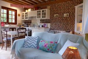 a living room with a blue couch and a kitchen at La Flore De Lys in Saint-Jouin-Bruneval