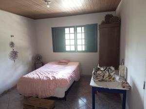 a bedroom with a bed and a table and a window at Chácara c piscina in Cotia +8 photos