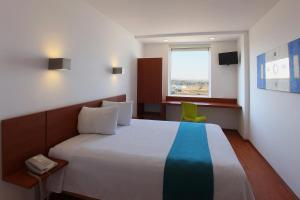 a bedroom with a large bed and a green chair at One Queretaro Aeropuerto in Querétaro +38 photos