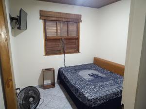 a small bedroom with a bed and a window at Chácara c piscina in Cotia