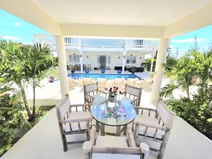 a patio with a table and chairs and a pool at The Babbington Villa in Taylor Bay Beach