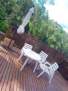 two chairs and a table and an umbrella on a deck at Chácara c piscina in Cotia