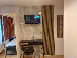 a room with a desk with a television on a wall at Pension Alpha in Frankfurt