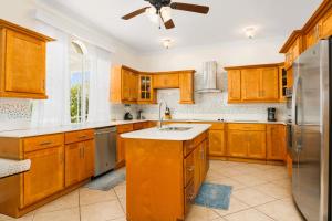 a large kitchen with wooden cabinets and a sink at The Babbington Villa in Taylor Bay Beach