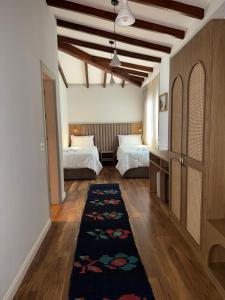 a bedroom with two beds and a rug on the floor at Hani i Gjelit Hotel, Korce in Korçë +68 photos