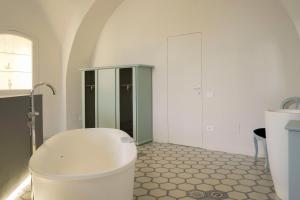 a white bathroom with a tub and a glass cabinet at Viaggio Homes Appartamenti da 60 m2 con Jacuzzi Hammam Cucina Patio con Aperitivo di Benvenuto in Faiano