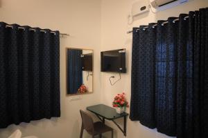 a room with black curtains and a table and a television at Skytouch Residency-OMR in Chennai +15 photos