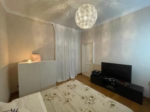 a room with a bed and a television and a chandelier at Paradise Suites - Brignole Station - Best Price Rooms - ALWAYS OPEN in Genoa