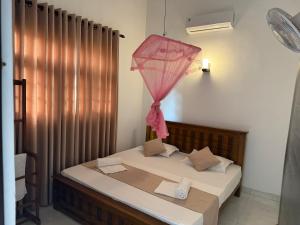 a bedroom with a bed with a pink umbrella at Zuulas Palace in Dickwella