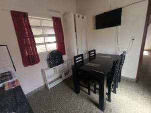 a dining room with a black table and chairs and a television at Deptos Pablos, Apto No 4 in Villa Gesell