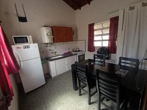 a kitchen with a table and a white refrigerator at Deptos Pablos, Apto No 4 in Villa Gesell