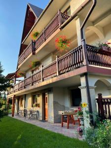 a building with a balcony with tables and chairs at Domek pod Maciejową in Rabka-Zdrój